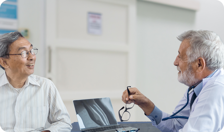 Two older men are having a discussion sitting across from one another. The man on the right is a Beltone audiology specialist, and the man on the left is a patient.