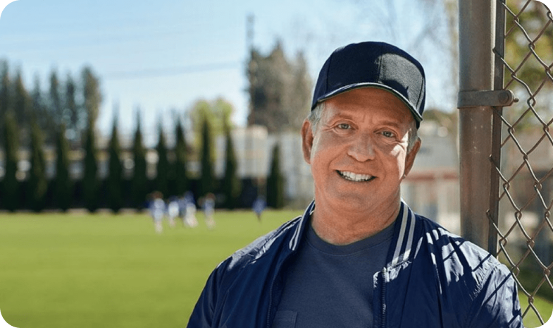 coach posing outside of baseball field