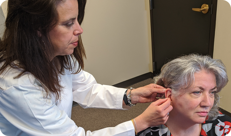 A Beltone specialist measures a patient's ear for fitting a custom hearing aid after a hearing test. 