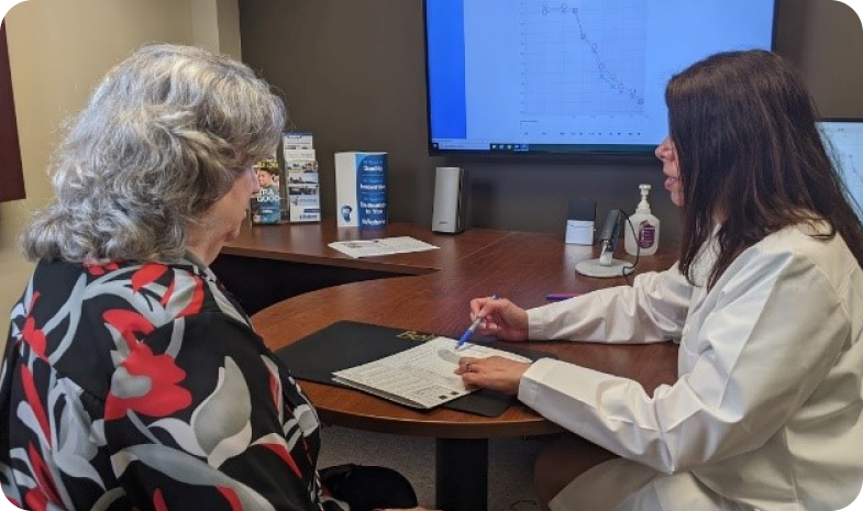 A Beltone specialist reviews the results of a hearing test with the patient. They sit in an office, reviewing paperwork.