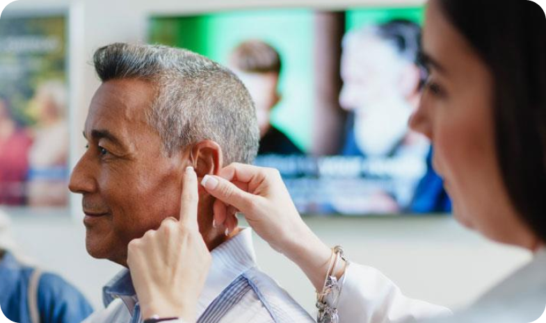 A Beltone specialist examines a patient's ear. She's using her hands to feel around the patient's ear lobes.