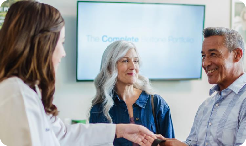 A middle-aged couple discuss hearing aid financing options with a Beltone specialist.