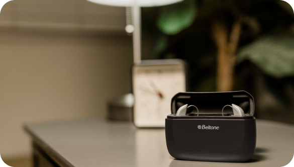 The Beltone Achieve hearing aid system pictured in it's storage case, sitting on a gray table.